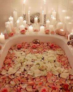 a bathtub filled with lots of flowers and candles