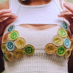 a woman wearing a white tank top with buttons on her chest and two hands over her shoulder