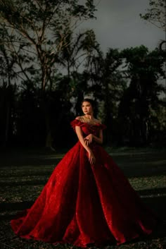 a woman in a red dress is posing for a photo with trees in the background