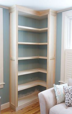 an empty living room with blue walls and white furniture in the corner, along with wood flooring