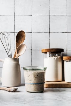 two jars with spoons are sitting next to each other on a white countertop