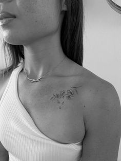 a woman with a flower tattoo on her chest looking off into the distance while standing in front of a mirror