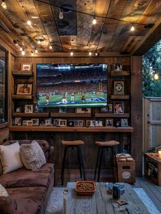 a living room filled with furniture and a flat screen tv mounted to the side of a wooden wall