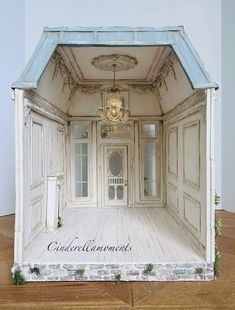 an open door to a room with white walls and wood flooring is shown in front of a chandelier