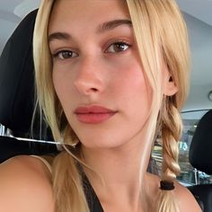 a woman sitting in the back seat of a car with blonde hair and braids