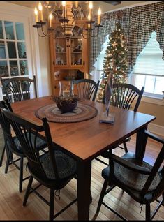 a dining room table with chairs and a christmas tree in the corner on top of it