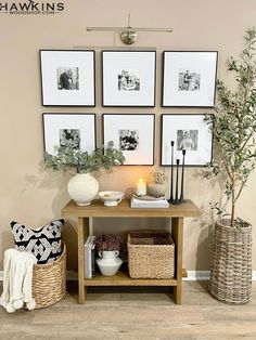 a living room with pictures on the wall and wicker baskets under it, along with two vases filled with flowers