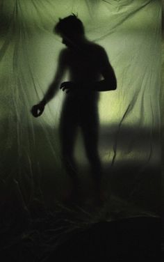 the shadow of a man standing in front of a curtain with his hands on his hips