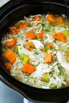 a crock pot filled with chicken, rice and carrots