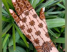 a woman's hand with henna on it and palm leaves in the background