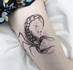 a black and white scorpion tattoo on the right thigh, with stars in the background