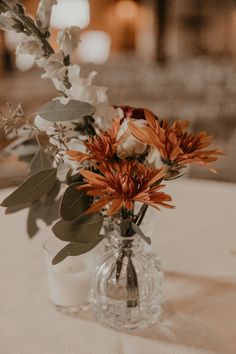 a vase filled with flowers sitting on top of a white table cloth covered tablecloth