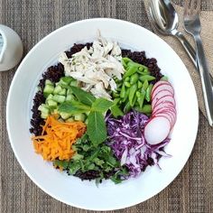 a white plate topped with lots of veggies next to a fork and knife