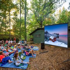 people sitting on blankets watching a movie in the woods