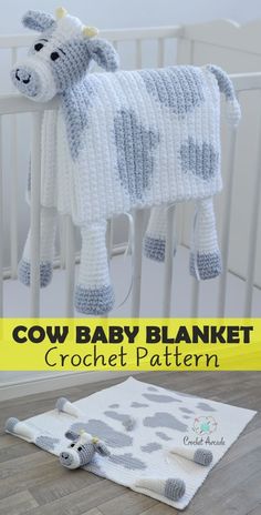 a crocheted cow baby blanket sitting on top of a wooden floor next to a white crib