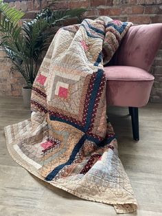 a chair with a blanket on it next to a brick wall and potted plant