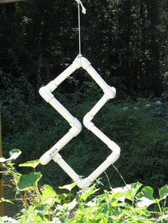 a wind chime made out of pipes hanging from a wire in front of some trees