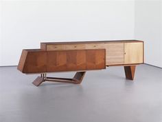 a wooden desk with drawers on it in an empty room and white walls behind it