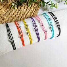 six different colored bracelets are lined up on a white towel next to a basket