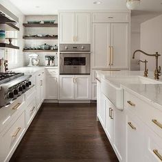 a kitchen with white cabinets and gold pulls on the handles, along with wood flooring