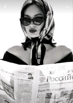 a woman wearing sunglasses and a scarf reading a newspaper