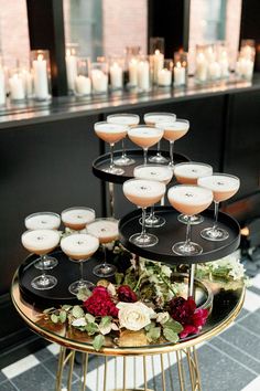 a table topped with lots of glasses filled with drinks and flowers on top of it