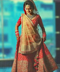 a woman in a red and gold bridal gown with her hands on her hips