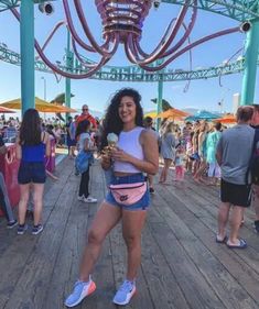 a woman holding an ice cream cone standing on a wooden deck with people in the background