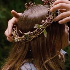 a close up of a person wearing a wreath of flowers on their head and hands