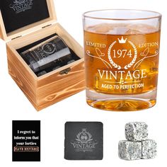 an old fashioned whiskey glass with ice cubes next to it and a wooden box