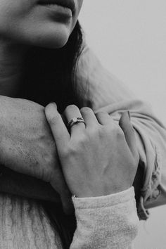 black and white photograph of a woman with her hand on her shoulder, wearing a ring