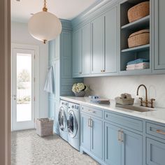 a laundry room with blue cabinets and washer and dryer in the corner, next to an open door