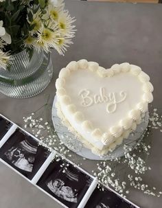 a heart shaped cake sitting on top of a table next to flowers and photos with baby's breath written on it