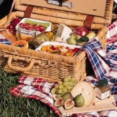 a picnic basket filled with food sitting on the grass