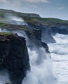 the cliffs are covered in water as waves crash against them and people stand on the cliff edge