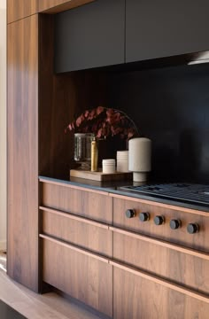 a stove top oven sitting next to a wooden cabinet with vases and candles on it