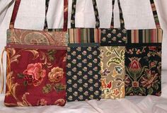 four purses are lined up on a white cloth covered tablecloth with floral designs