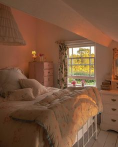 a bed sitting under a window in a bedroom next to a dresser with drawers and lamps