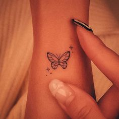 a woman's wrist with a small butterfly tattoo on the left side of her arm