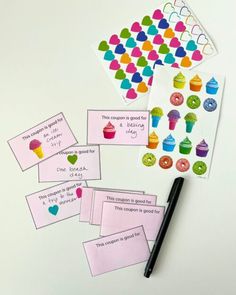 some cards and pens on a table with cupcakes