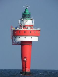 a red and white lighthouse in the middle of the ocean