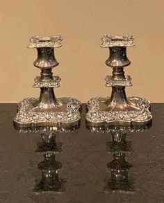 two silver candlesticks sitting on top of a table