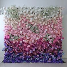 the wall is made up of many different colors and sizes of flowers, including pinks, purples, and white