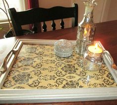 a tray that has some candles on top of it and a glass container next to it