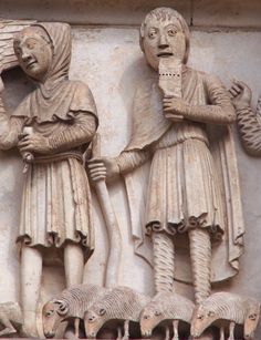 two statues on the side of a building, one holding an object in his hand