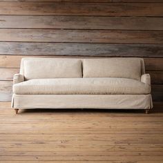 a couch sitting on top of a hard wood floor next to a wall with wooden planks