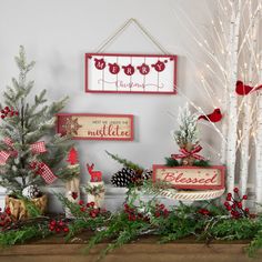 christmas decorations are displayed on the mantle in front of a tree and other holiday items