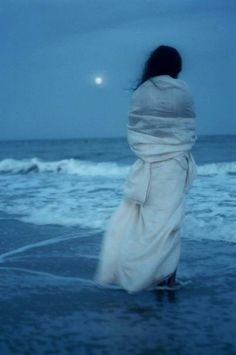 a woman standing on top of a beach next to the ocean