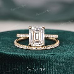 an emerald colored diamond engagement ring set on top of a green velvet cushioned box