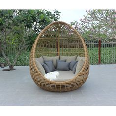 a wicker hanging chair with cushions and pillows